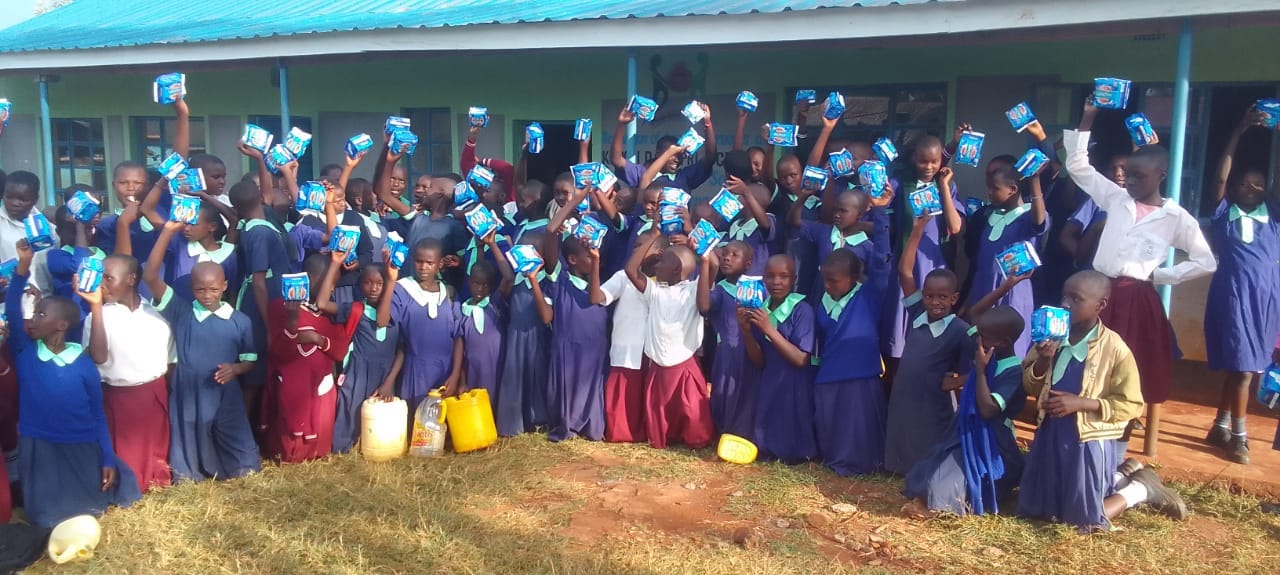 Pupils gathered outside the classrooms at Kiorori Primary School, holding up packets of sanitary pads.